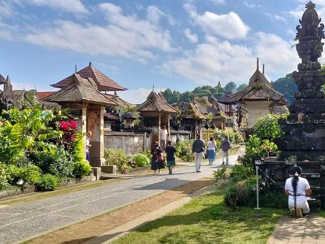 Menschen gehen auf einem Steinweg in einem traditionellen balinesischen Dorf.