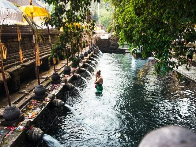 An elderly woman making offerings out of woven palm leaves.