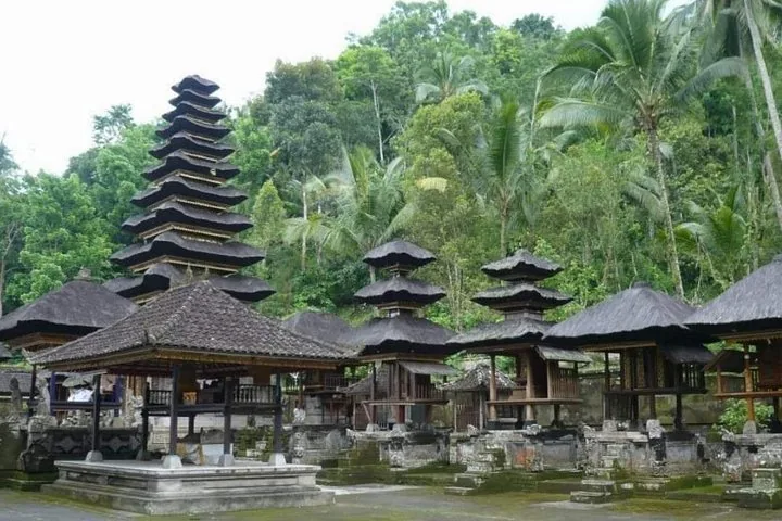 Strutture tradizionali di templi balinesi con tetti di paglia a più livelli circondati da alberi.