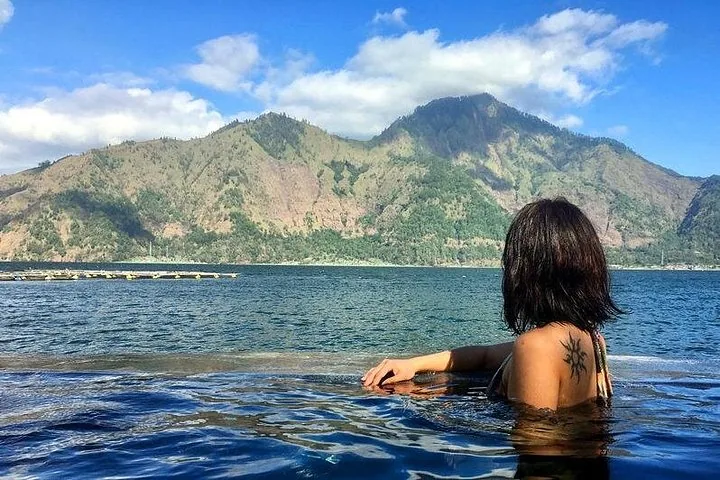 Eine Frau entspannt sich in einem Pool mit Blick auf einen See und Berge.